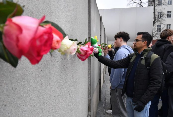 36th Anniversary of Berlin Wall Fall People place flowers to mark the 36th anniversary of the Berlin wall fall, at the Wall memorial on Bernauer Strasse. Credit: Paul Zinken/dpa