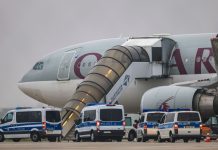 Deportations from Germany rise sharply over past two years FILED - Police vehicles stand in front of a Qatar Airways plane at Leipzig/Halle Airport. Photo: Jan Woitas/dpa