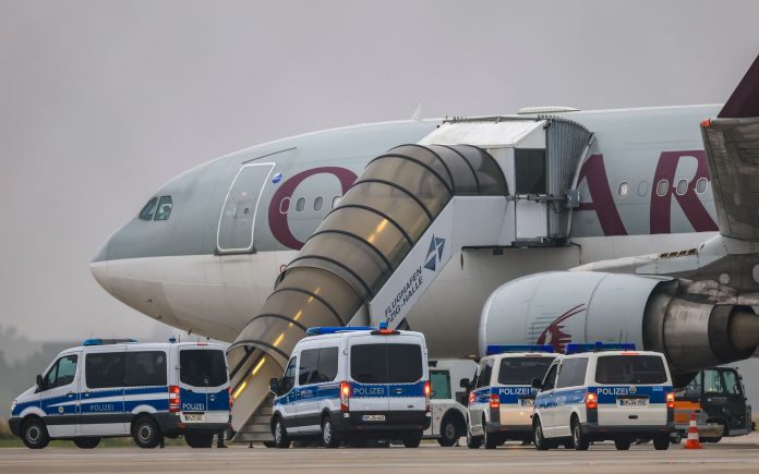 FILED - Police vehicles stand in front of a Qatar Airways plane at Leipzig/Halle Airport. Photo: Jan Woitas/dpa